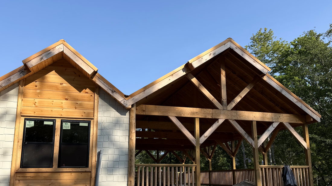 Twin timber-frame gables with exposed trusses over a covered porch, cedar shake and stained siding, under construction in Sevier County, Tennessee.