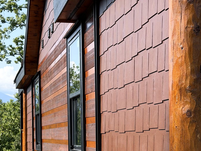 Cedar shake over stained horizontal lap siding meeting a full-round log corner post.
